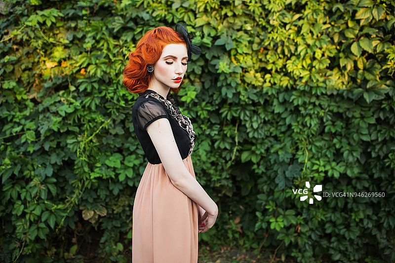红头发的女孩在一个夏天的公园背景下，自由飞翔的裙子和复古的发型。图片素材