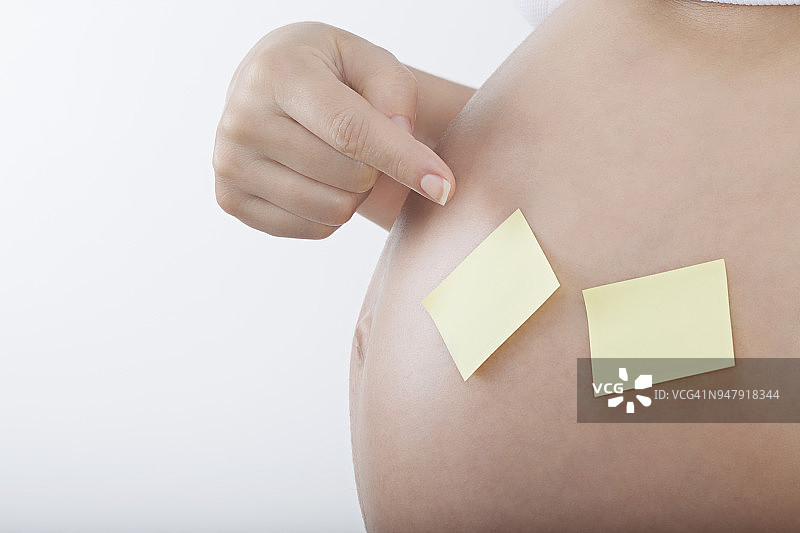 孕妇指着纸笔记在肚子里图片素材