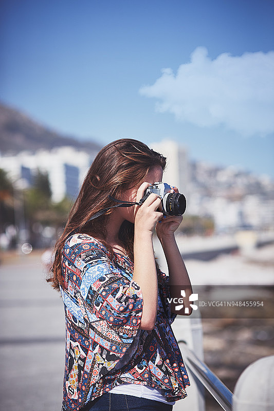 年轻的女摄影师在海滩上拍照图片素材