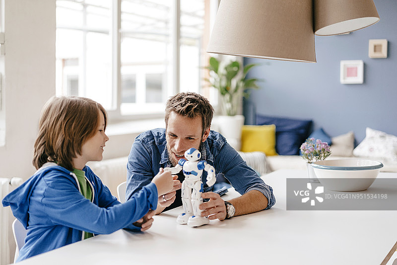 快乐的爸爸和儿子在家里的桌子上玩机器人图片素材
