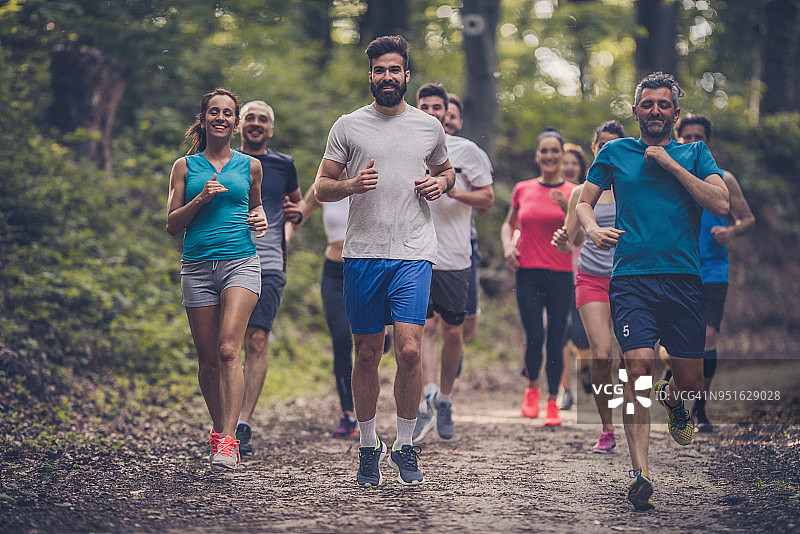 一群快乐的运动员在森林里跑马拉松。图片素材