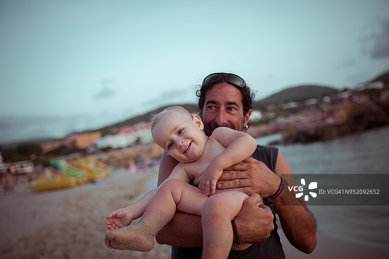 在海滩上，一个男人抱着他的小侄子图片素材