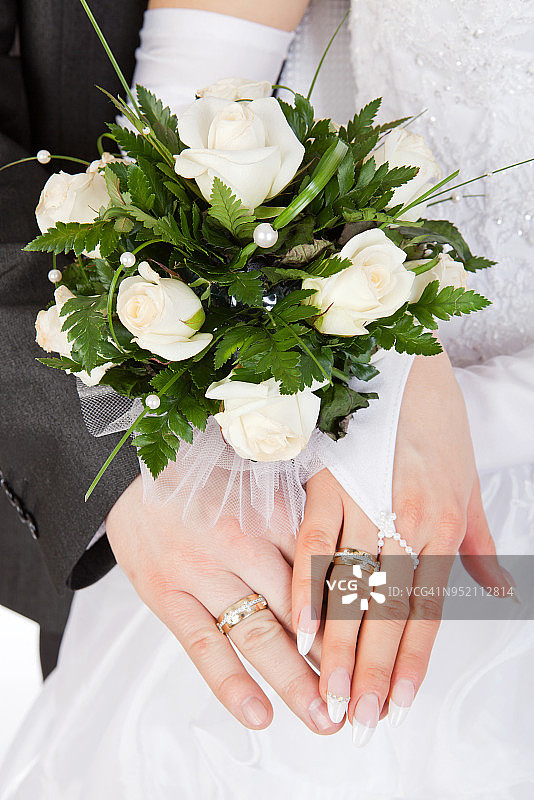 新郎和新娘的手拿着戒指和婚礼花束图片素材