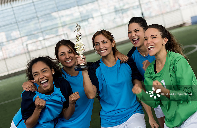 快乐的女足队员们拿着奖杯庆祝图片素材