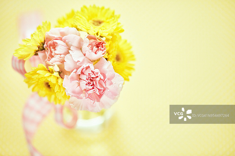一束粉红色和黄色的花放在一个简单的玻璃瓶里图片素材