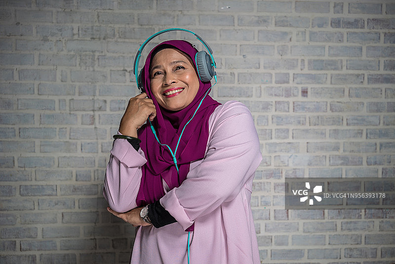 马来族妇女用耳机欣赏音乐图片素材