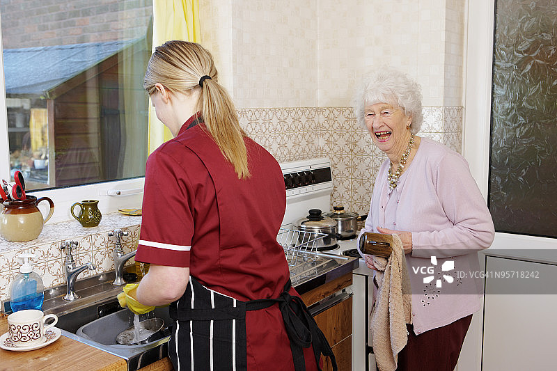 护士和快乐的老女人在厨房洗碗图片素材