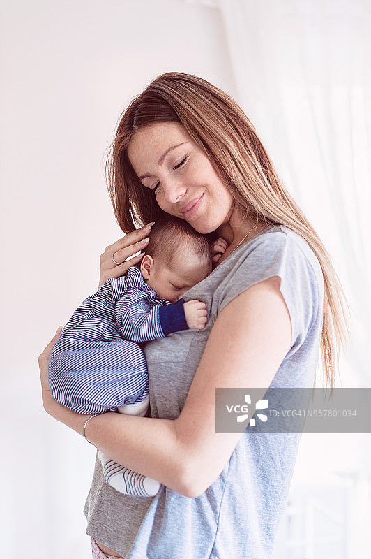 一个美丽的年轻母亲抱着她刚出生的婴儿的肖像图片素材