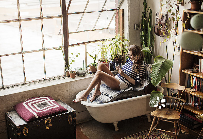 高角度的女人坐在客厅的浴缸沙发上图片素材
