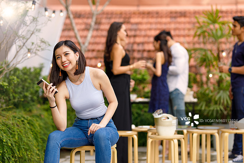 年轻的亚洲女性在户外屋顶派对上与朋友使用电话图片素材