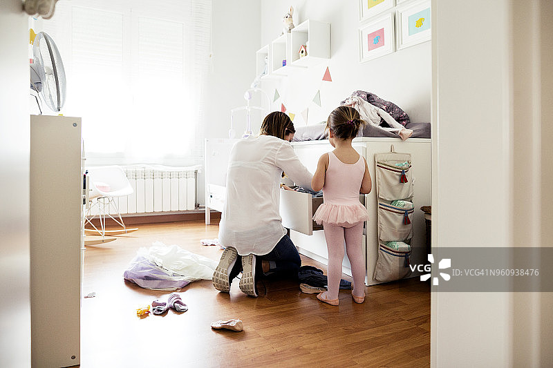 后视图母亲在抽屉里寻找女儿穿着芭蕾短裙在卧室里图片素材