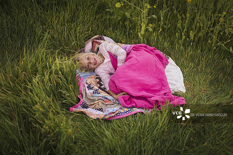 高角度的肖像快乐的女孩躺在毯子在草地图片素材
