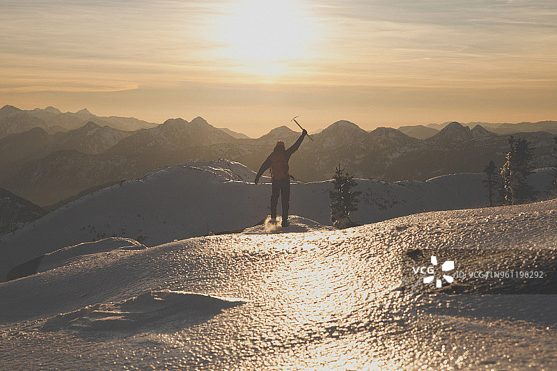 后视图的徒步者与冰斧登山在雪山在日落图片素材