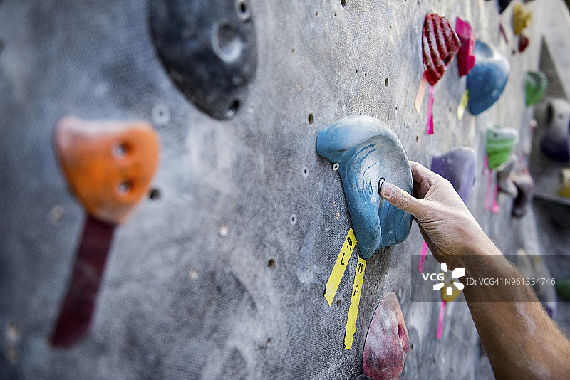 裁剪图像的运动员抱着岩石在攀岩墙图片素材