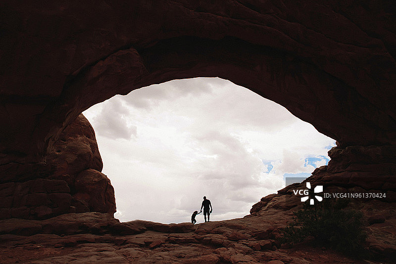 阴天下，父女站在岩石上的剪影图片素材