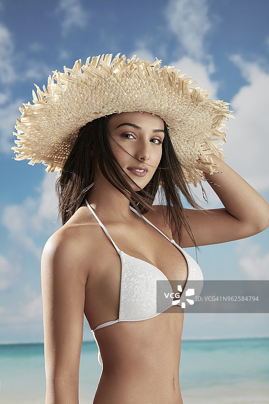 在热带海滩上戴着帽子的黑发女人图片素材