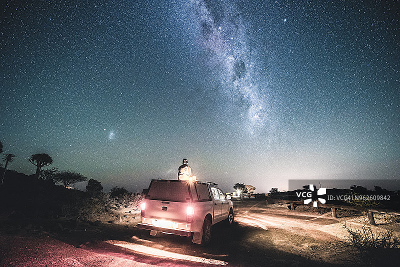 一名男子坐在银河下的四驱车车顶上图片素材