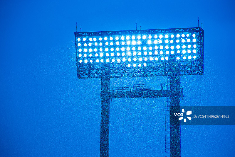 大雨滂沱，足球场聚光灯下得很亮。图片素材
