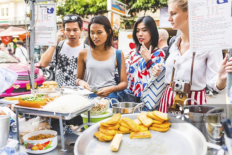 泰国，曼谷，考山路，一群朋友在街头市场上选择当地的食物图片素材
