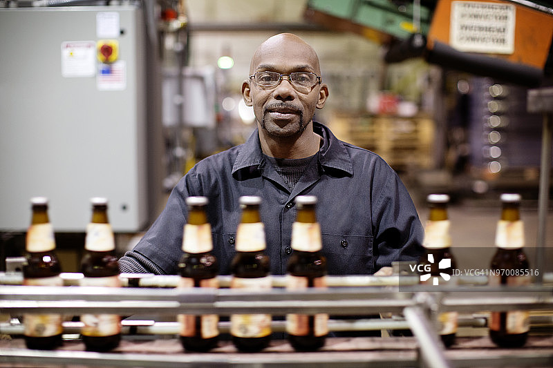 工人站在啤酒厂装瓶厂旁的肖像图片素材