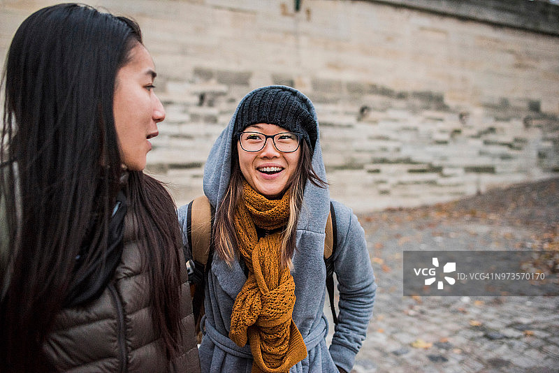 两名年轻的女游客在河岸上聊天，法国巴黎图片素材