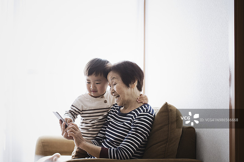 祖母和男孩在家里一起使用智能手机图片素材