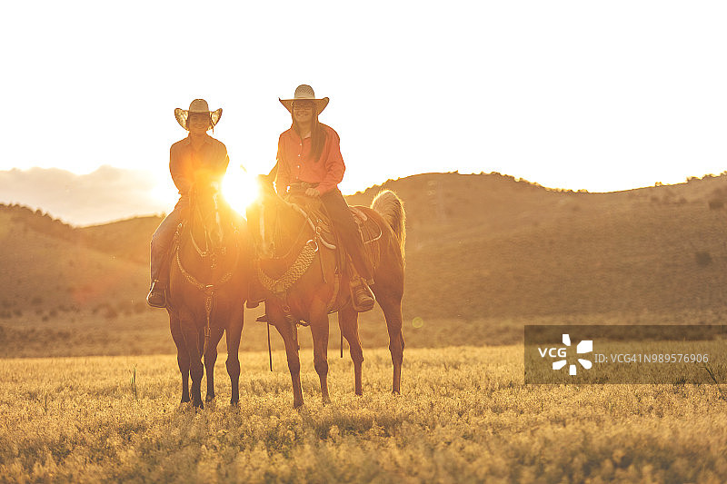 犹他州的女牛仔在日落西部户外和牛仔竞技会上踩踏，放牧的马图片素材