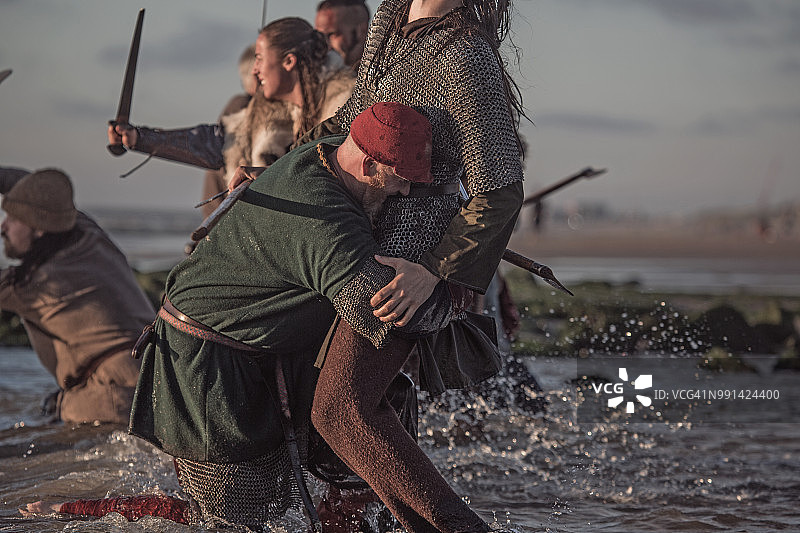 一群挥舞着剑的中世纪维京战士在寒冷的海滩上厮杀图片素材