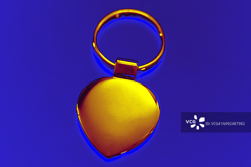 彩色处理图像的金色心形金属钥匙环在蓝色背景下发光图片素材