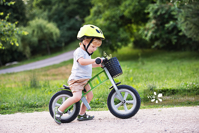 一个蹒跚学步的小男孩在户外骑着平衡自行车。图片素材