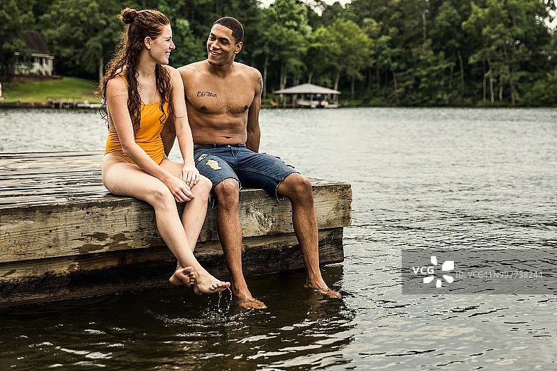 一对年轻夫妇坐在湖边的码头上图片素材