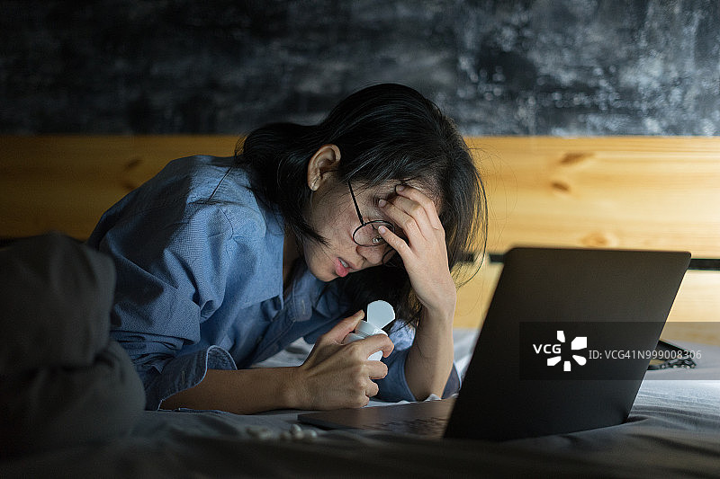 亚洲女性非常紧张和头痛的笔记本电脑在晚上的时间图片素材