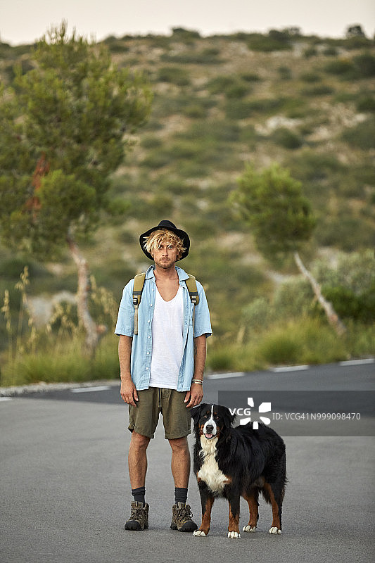 徒步旅行者和狗站在路上的肖像图片素材