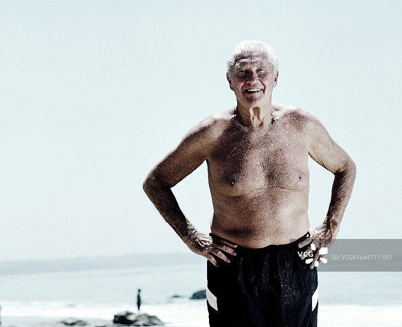 老人站在沙滩上，双手叉腰，画像图片素材