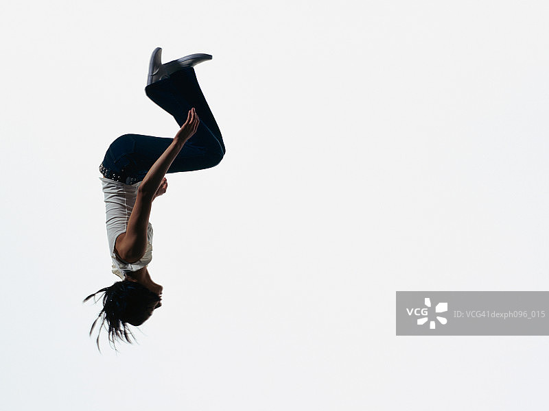年轻的亚洲女孩穿着牛仔裤和t恤，跳在半空中图片素材