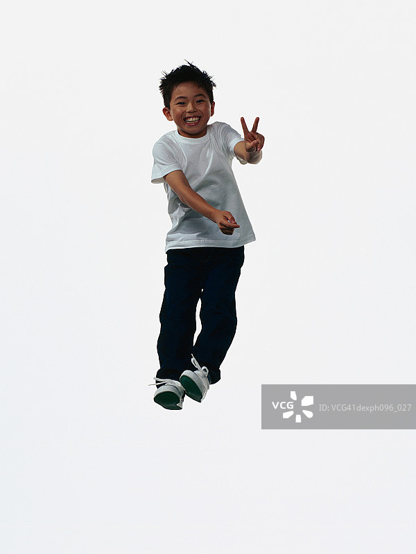 年轻的亚洲男孩穿着牛仔裤和t恤，跳在半空中图片素材