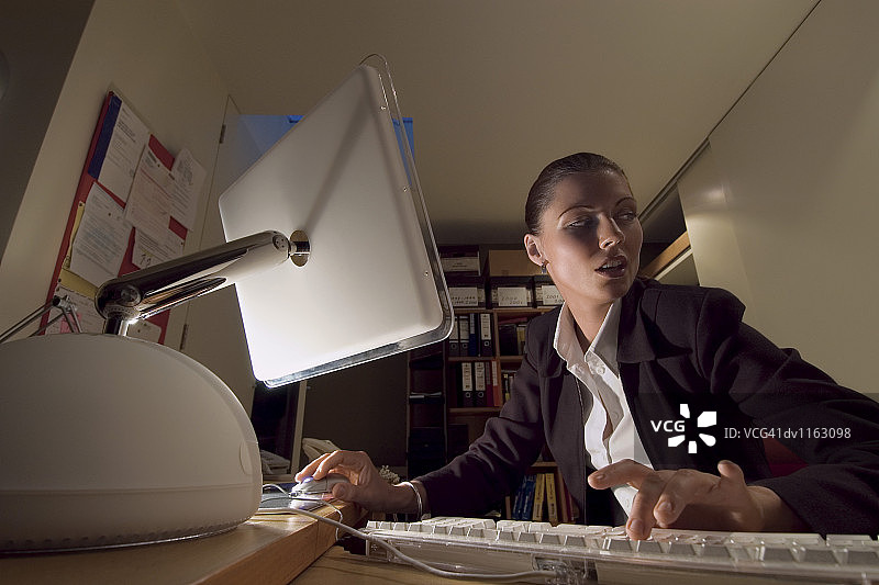 坐在办公室里使用电脑的可疑女商人图片素材