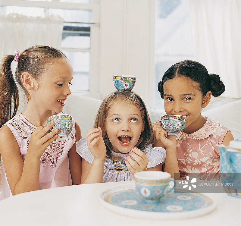 三个女孩并排坐着，一起开茶话会，一起玩乐图片素材