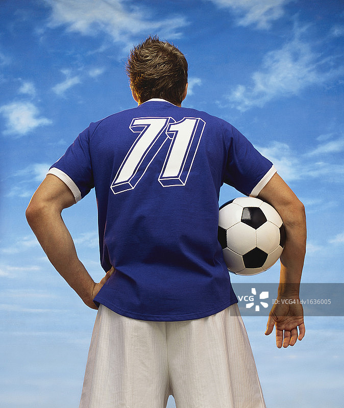 一个足球运动员抱着足球的后视图图片素材
