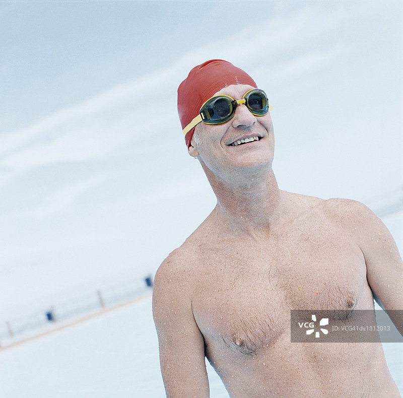 一个成年人戴着游泳帽和泳镜站在游泳池里图片素材
