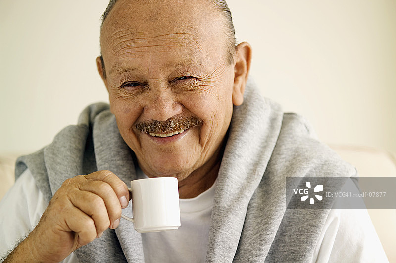 微笑的老人拿着咖啡杯，特写图片素材