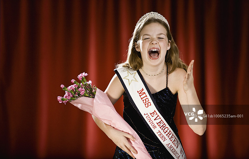 女孩(11-13)在选美比赛中手持花束在舞台上尖叫图片素材