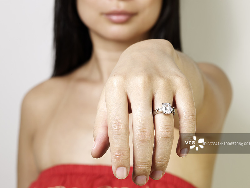 一个女人在手指上展示订婚戒指，特写图片素材