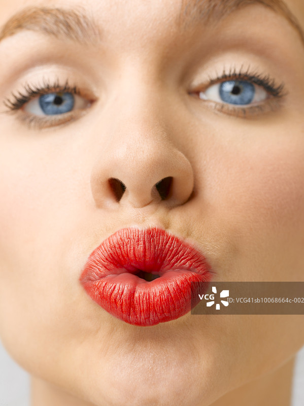 年轻女子的肖像，戴着红色唇膏亲吻，近距离，工作室拍摄图片素材