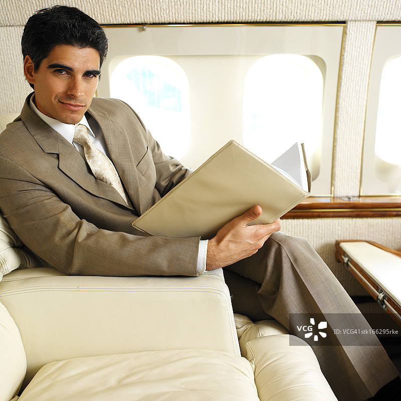 一个商人在飞机上拿着一本书的肖像图片素材
