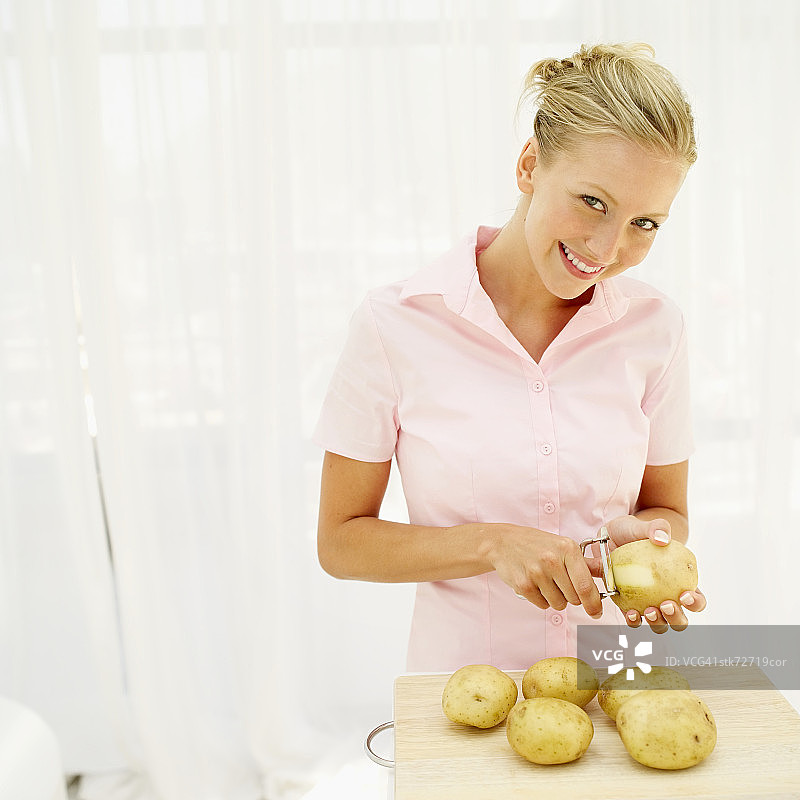 一个女人用削皮器削土豆的肖像图片素材