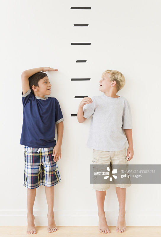 男孩子们根据墙上的标记测量自己图片素材