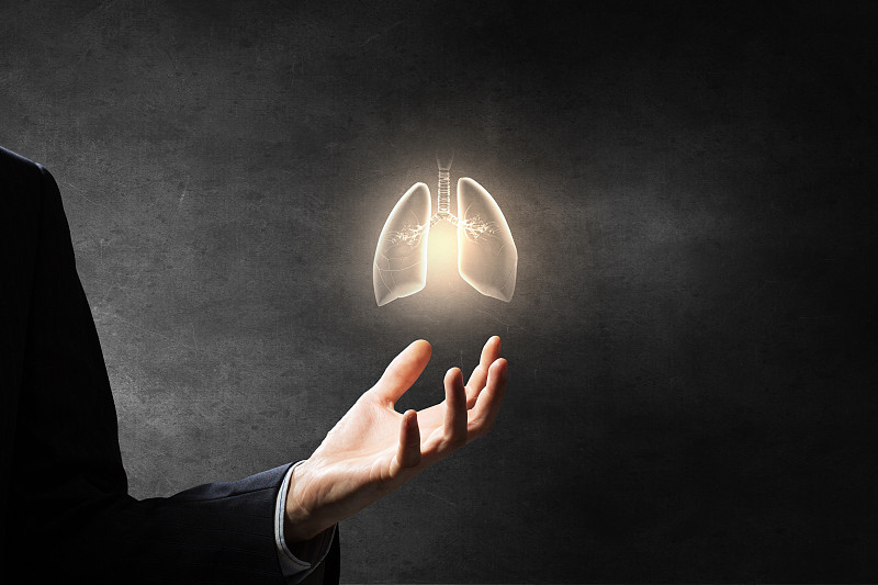 健康的肺和呼吸。男性的手在黑暗的背景持有肺符号图片素材