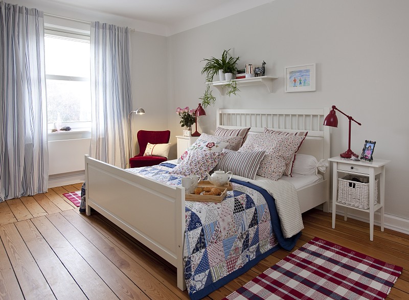 斯堪的纳维亚风格的卧室配有床、靠垫、扶手椅和边桌图片下载