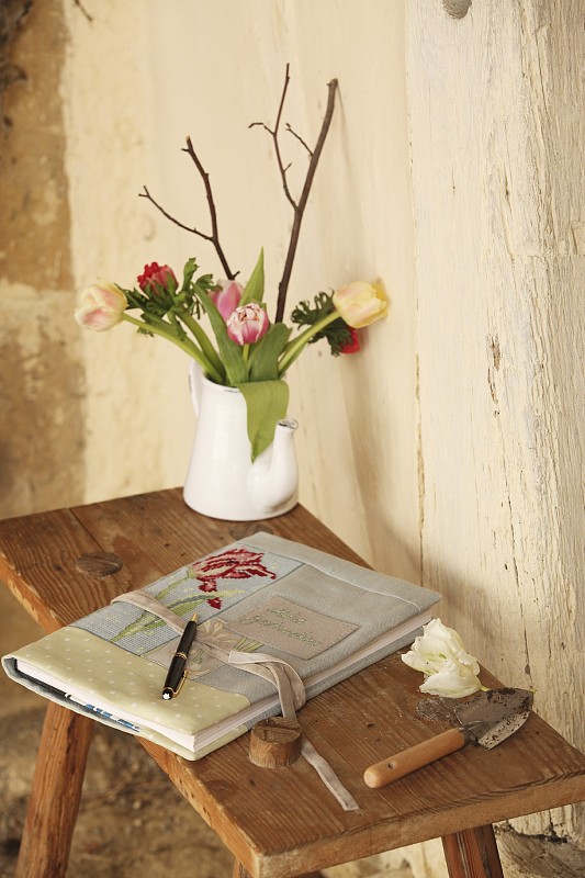 书是手工制作的，绣花布制的书夹和花瓶上的花，小，质朴的木桌图片下载